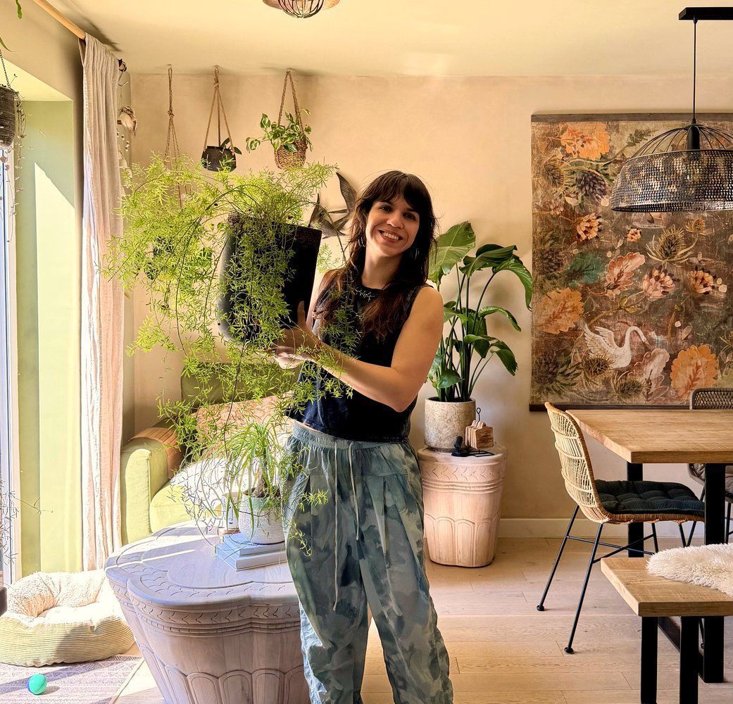 Mariné holding a plant in her home