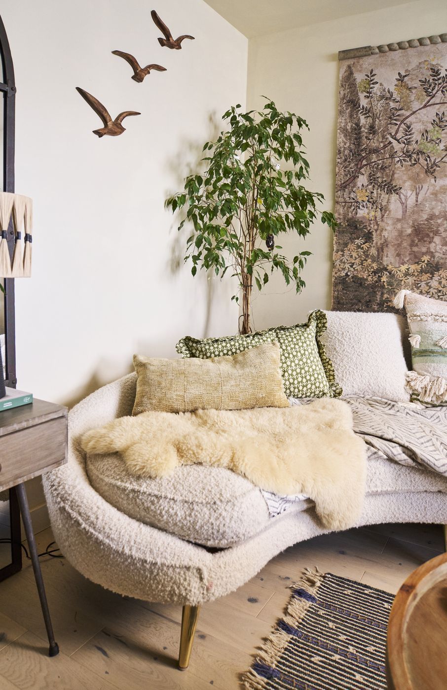Carved wooden bird silhouettes layered above soft boucle sofa textures