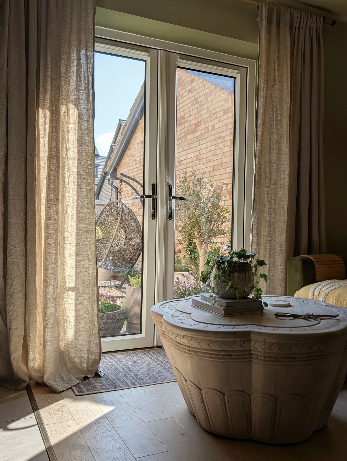 Linen curtains and French doors opening to the garden — a calm indoor-outdoor transition.