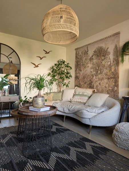 Living room with rattan lamp, curved sofa and tapestry